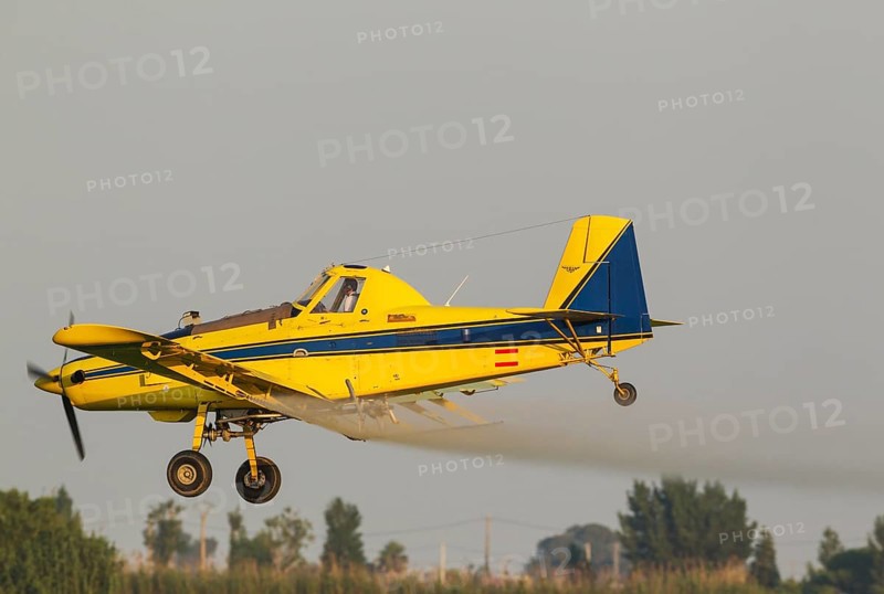 Crop duster plane flying low while spraying an anti mosquito substance onto the rice fields