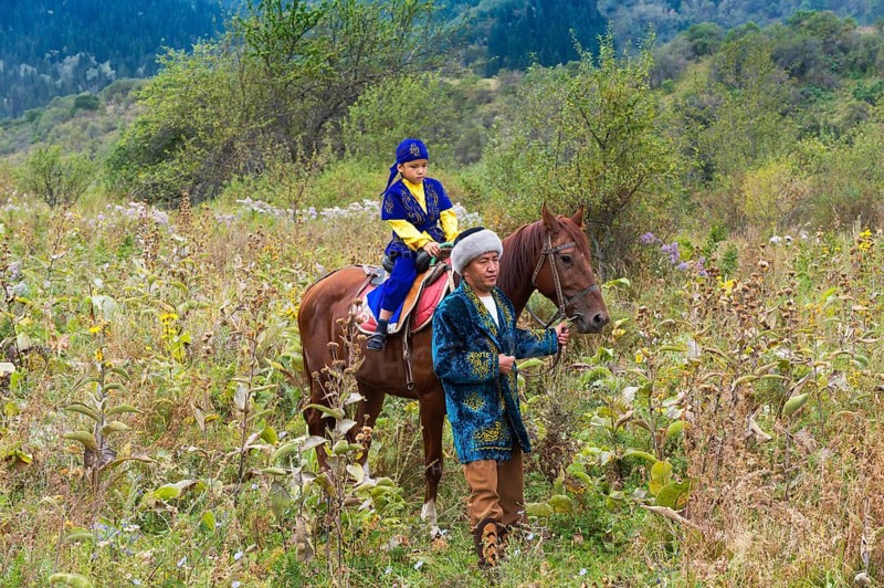 Kazakh man walking around with his son on a horse after Circumcision Sundet Toi ceremony