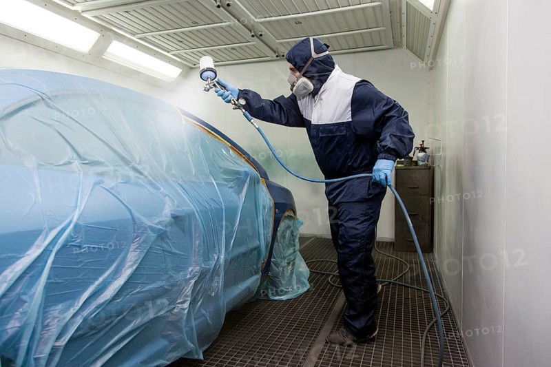 Vehicle painter during a partial painting of a car in the spray booth