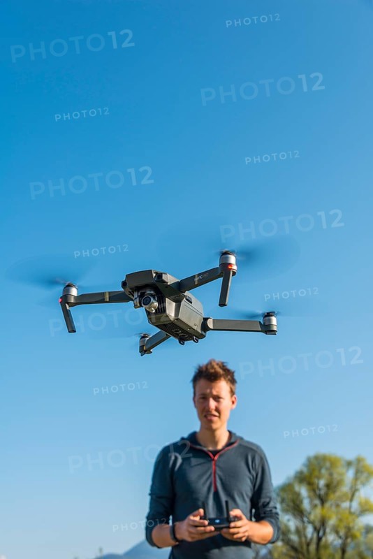 Young man controlling flying quadrocopter