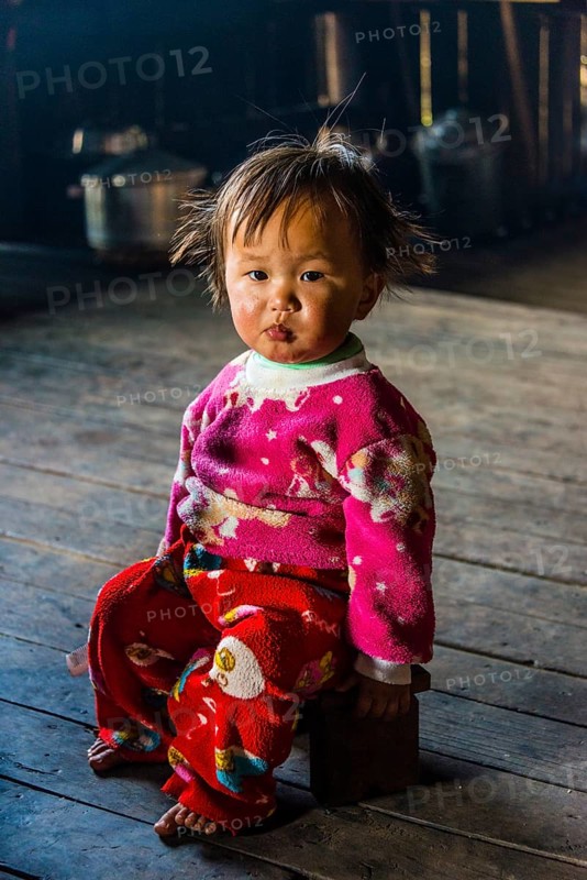 Little girl sits on stool in hut