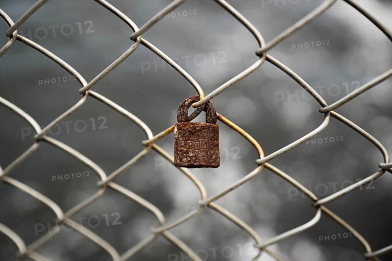 Rusty lock on chain-link fence
