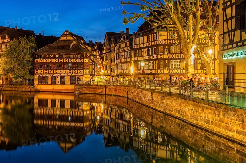 People on a restaurant terrace along the ILL canal at twilight