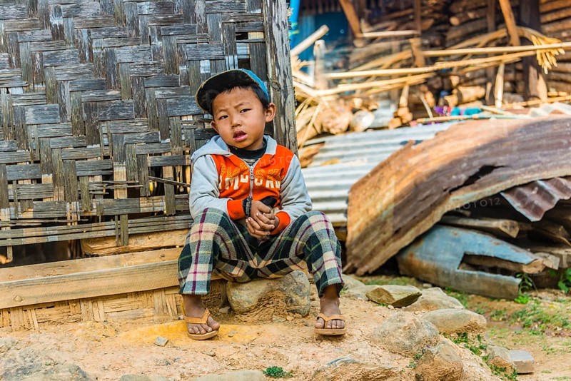 Little boy sitting in front of log cabin