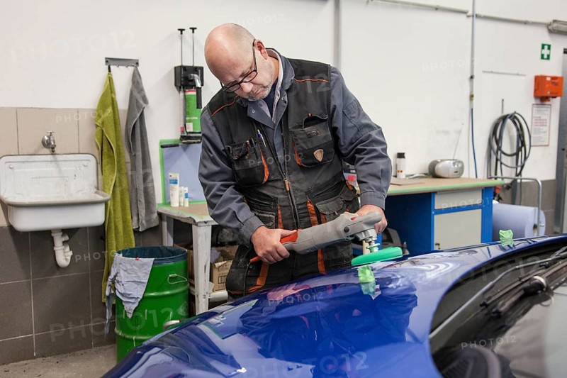 Coachbuilder master with the polishing machine on the car