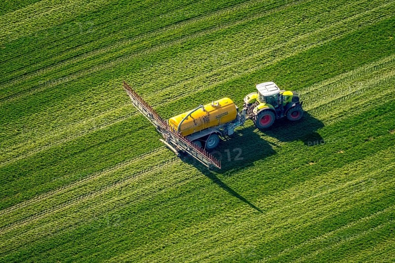 Tractor with pesticide sprayer on meadow