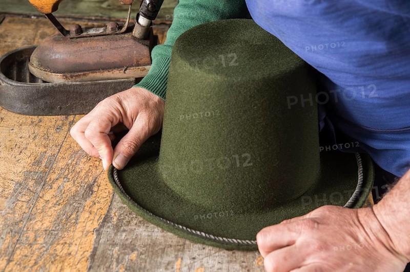 Hands holding cord on dry wool felt hat with shaped edge