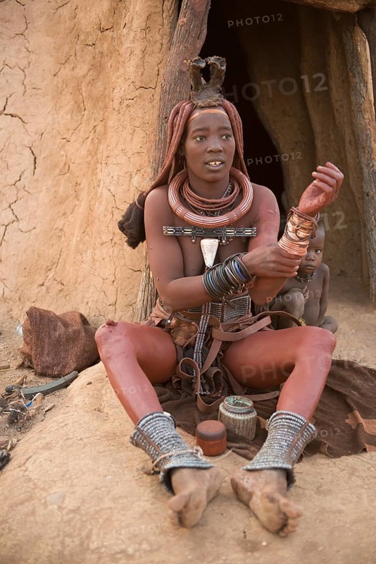 Himba woman with child in front of the hut