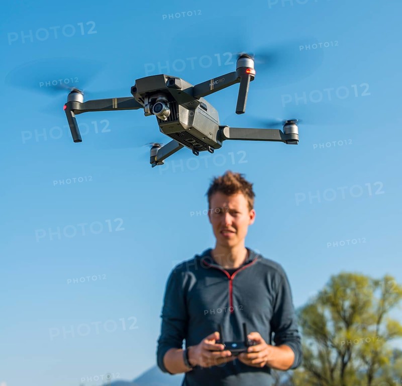 Young man controlling flying quadrocopter