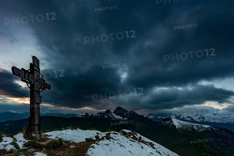 Cross on the summit of Zafernhorn with dark clouds