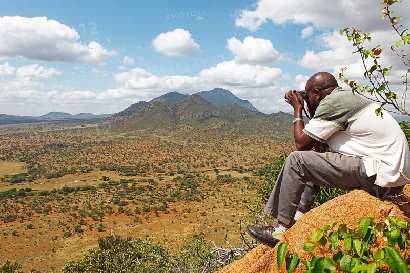 Man with binoculars looking at the Ngulia Hills and the Rhino Valley