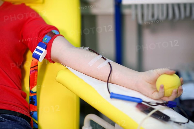 Patient with an infusion needle taking a blood sample at the transfusion ward of a hospital