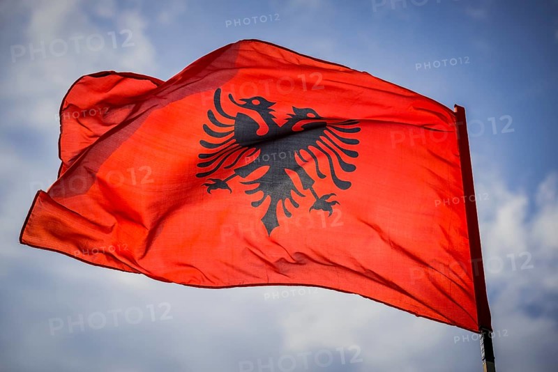 Waving Albanian flag with double eagle in front of blue sky