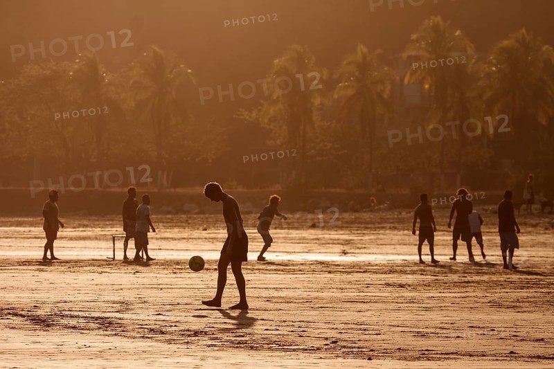 Young people playing football on the beach