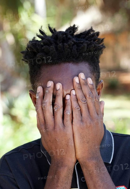 Namibian man of the Ovambo tribe holding hands in front of his face