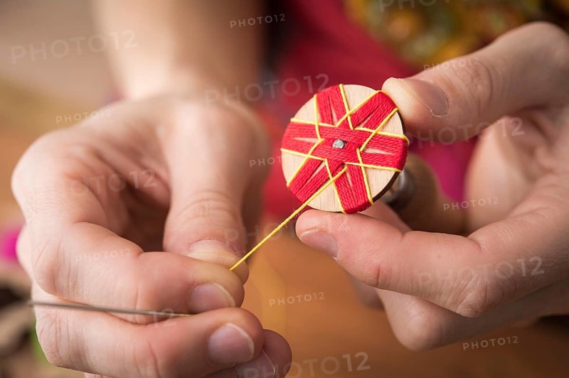 Button maker stitching and wrapping red and yellow yarn into star pattern