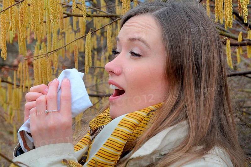 Woman with pollen allergy among flowering hazel (Corylus)