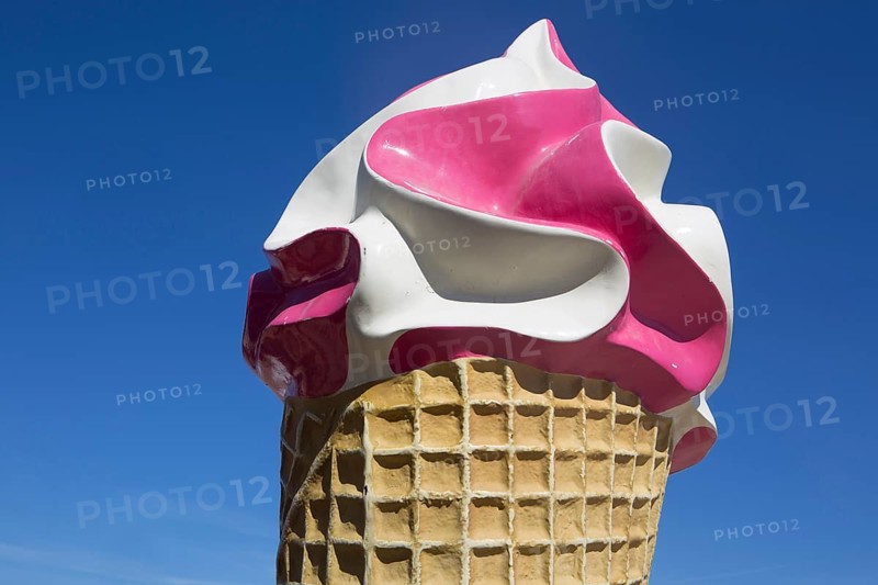 Large ice sculpture made of plastic as advertisement for an ice cream parlour in front of a blue sky