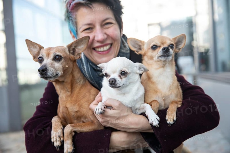 Laughing woman holding her three dogs in her arms