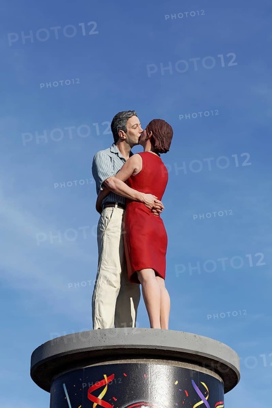 Kissing couple on an advertising pillar in front of a blue sky