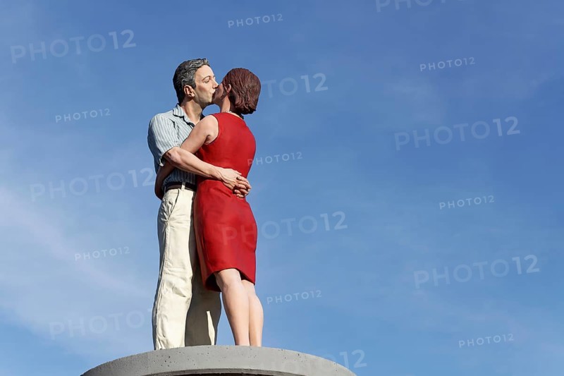 Kissing couple on an advertising pillar in front of a blue sky