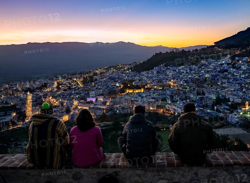 People sitting on a wall overlooking city Chefchauoen