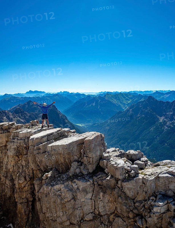 Hiker reaches arms into the air