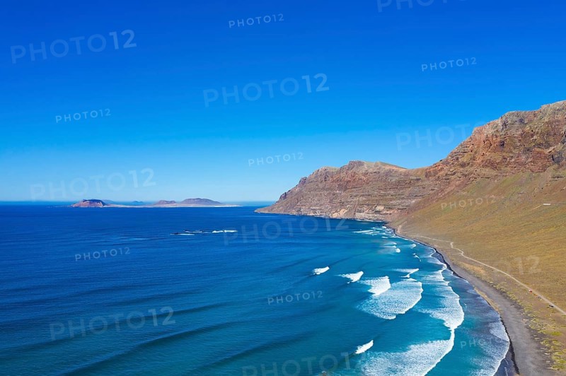 View on beach Playa Famara with mountain range Risco de Famara