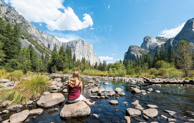 Young woman sitting on stone in River Merced