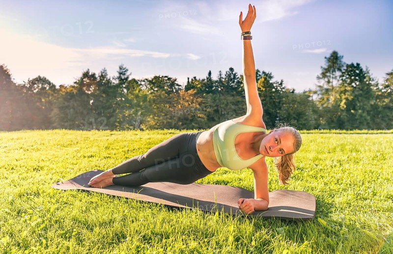 Young woman in sportswear doing side plank