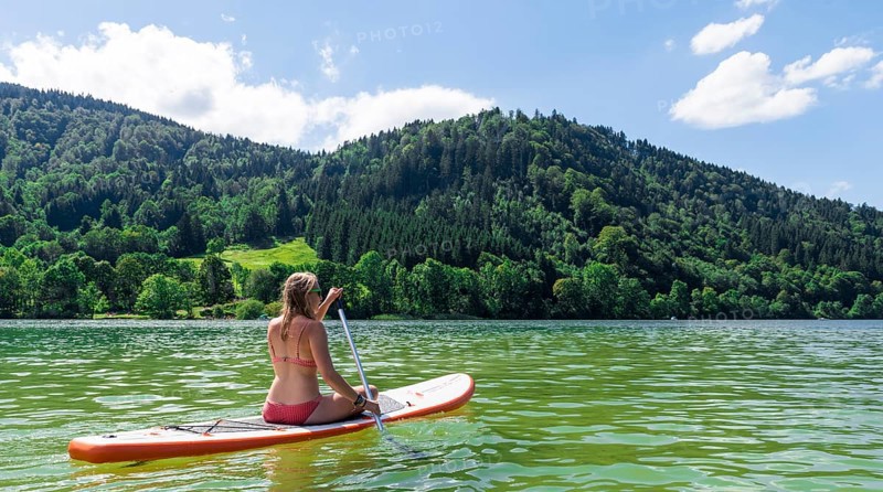 Young woman sitting on a Standup-Paddle Board or SUP