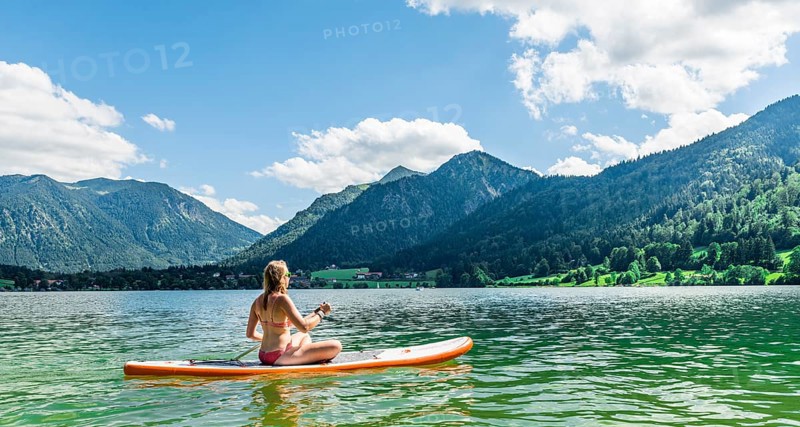 Young woman sitting on a Standup-Paddle Board or SUP