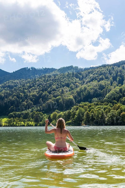 Young woman sitting on a Standup-Paddle Board or SUP