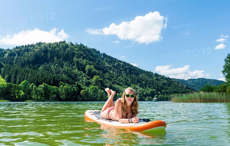 Young woman lying on a Standup-Paddle Board or SUP