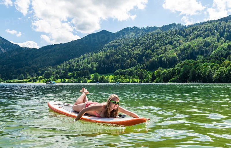 Young woman lying on a Standup-Paddle Board or SUP