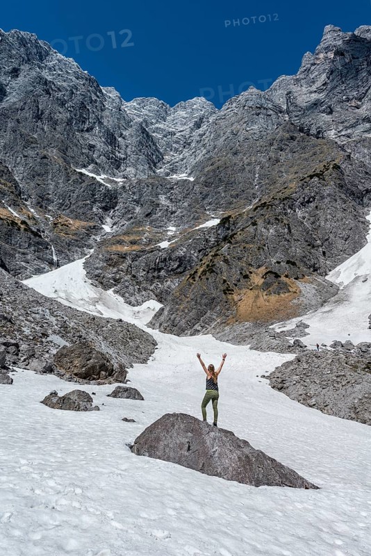 Hiker standing on rock with arms outstretched