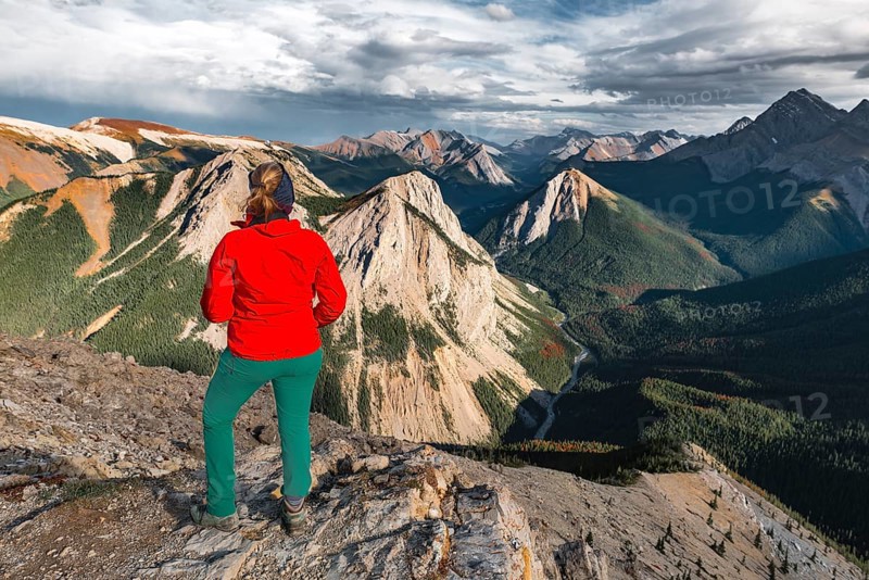 Female hiker looks from summit over mountain landscape