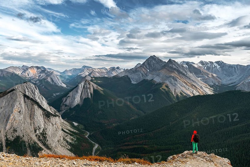 Female hiker views from summit over mountain landscape