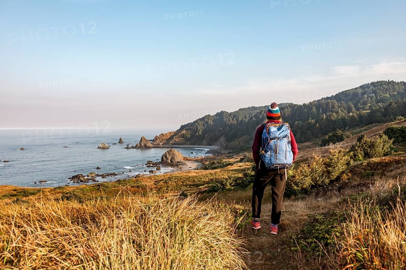 Young woman on a hiking trail along the rugged coast with many rocks