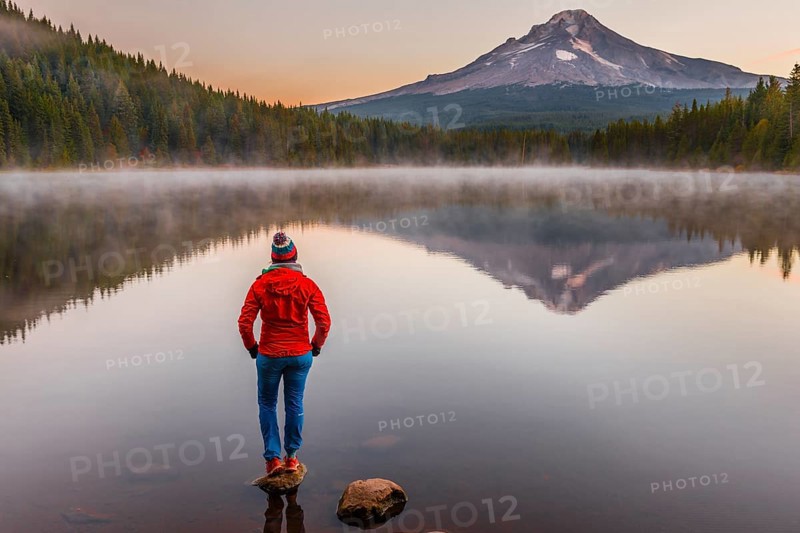 Young woman looking at view of volcano Mt. Hood with reflection in lake Trillium Lake