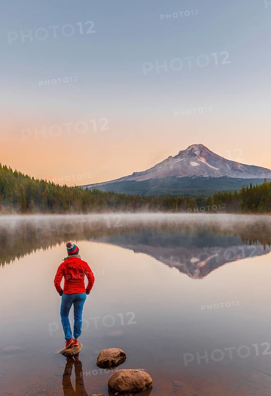Young woman looking at view of volcano Mt. Hood with reflection in lake Trillium Lake