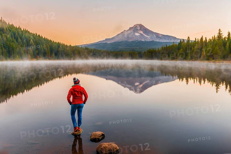 Young woman looking at view of volcano Mt. Hood with reflection in lake Trillium Lake