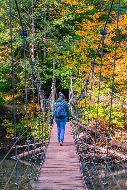 Young woman walking on a suspension bridge across a river