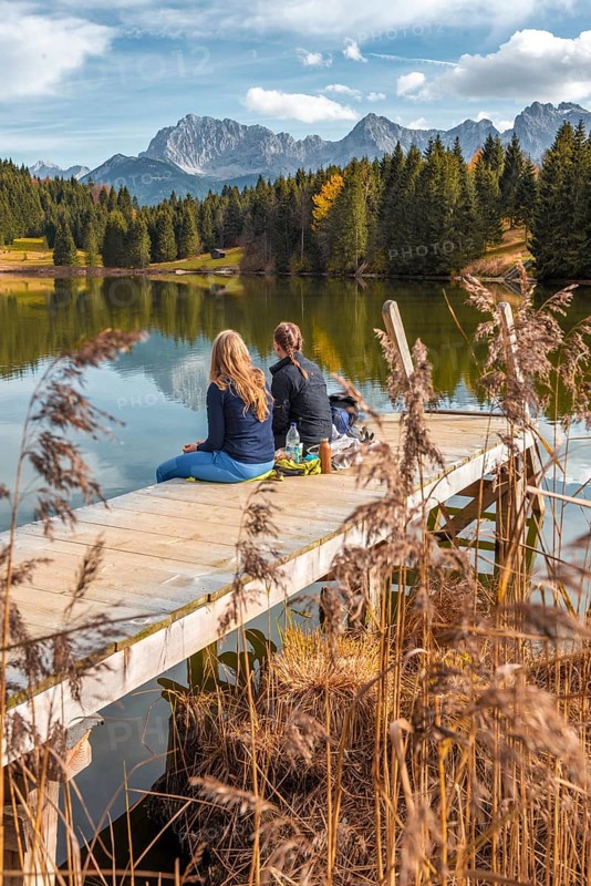 Two young women sitting at a jetty having a snack