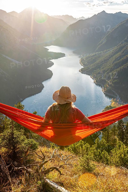 Woman with a sun hat sitting in an orange hammock