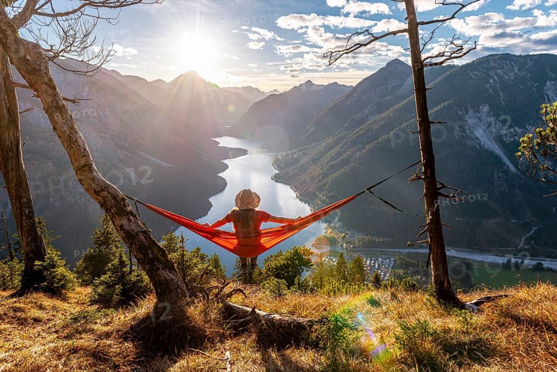 Woman with a sun hat sitting in an orange hammock