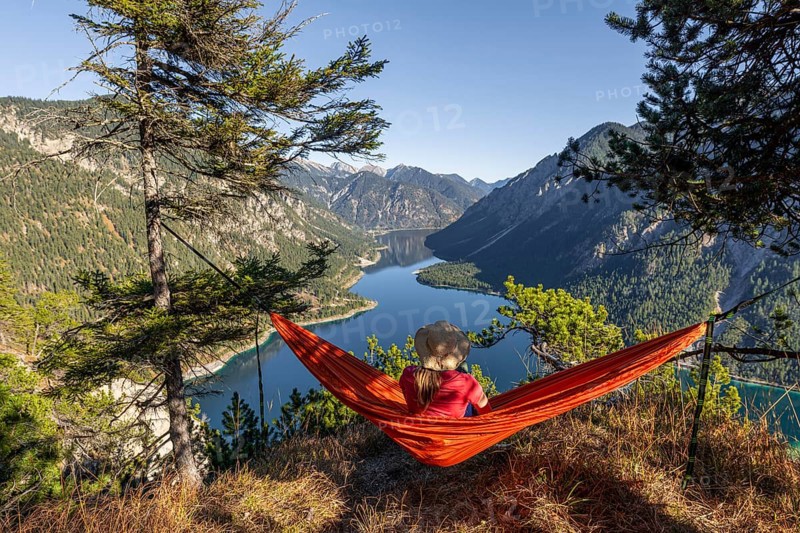 Woman with a sun hat sitting in an orange hammock