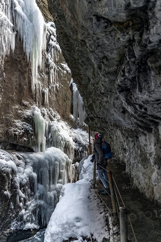 Young woman in the icy Partnachklamm with icicles and snow in winter