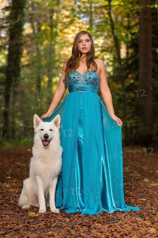 Woman with long turquoise-blue evening dress and white shepherd dog