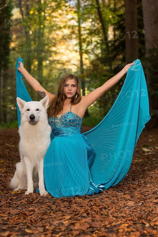Woman with long turquoise-blue evening dress and white shepherd dog